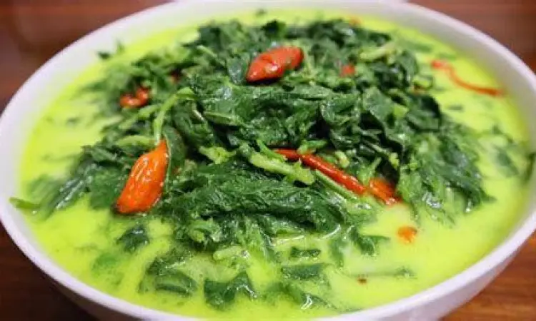 Mangkuk berisi sayur daun ubi tumbuk dengan kuah santan kuning