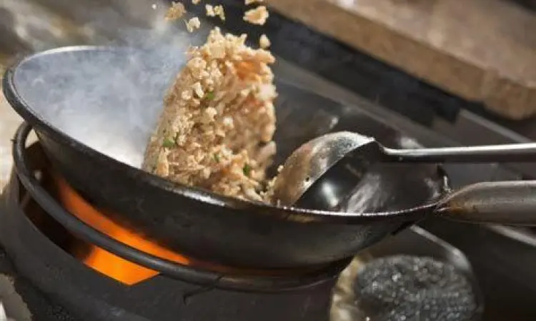 Proses memasak nasi goreng menggunakan wajan besar dengan api tinggi