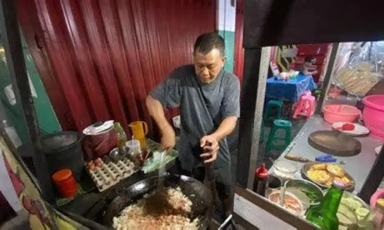 Pedagang nasi goreng sedang memasak dengan api besar