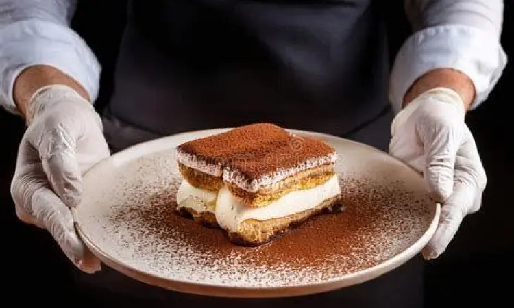 Sajian satu porsi tiramisu di piring dengan taburan kakao