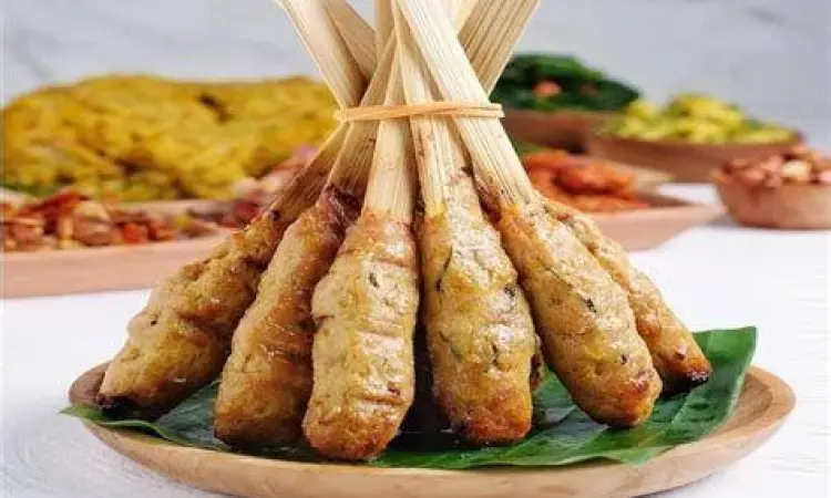 Proses melilitkan adonan sate lilit pada batang serai