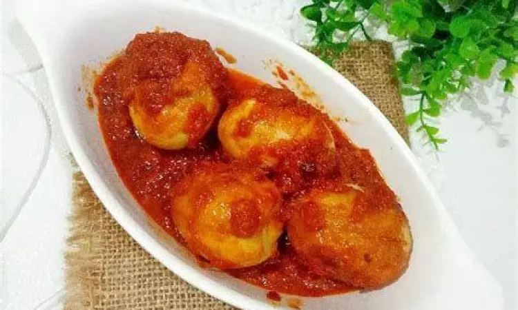 Piring saji berisi telur bumbu bali dengan garnish daun seledri