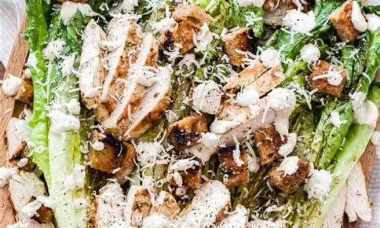 Plating Caesar Salad Ayam Caesar salad dengan topping dada ayam panggang di piring putih