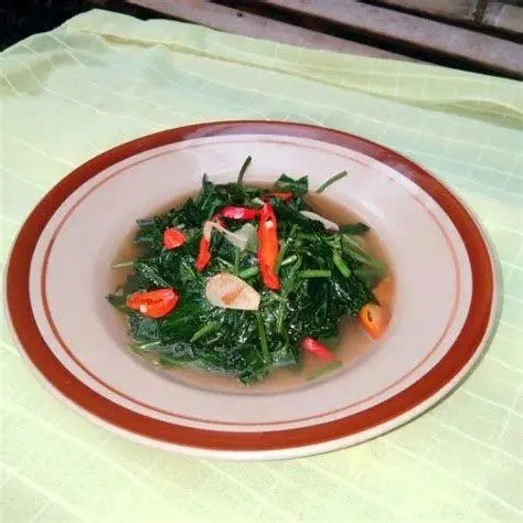 Hasil Jadi Tumis Daun Ubi Terasi Tumis daun ubi bumbu terasi di atas piring