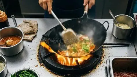 Aksi Stir Frying Profesional Koki profesional melakukan teknik stir frying dengan api besar