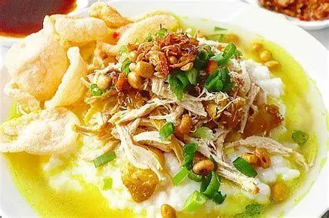 Bubur Ayam Kuah Kuning Sajian bubur ayam dengan kuah kuning yang kaya rempah